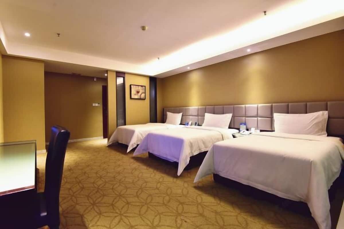 A hotel room with two beds, a desk, and a chair.
