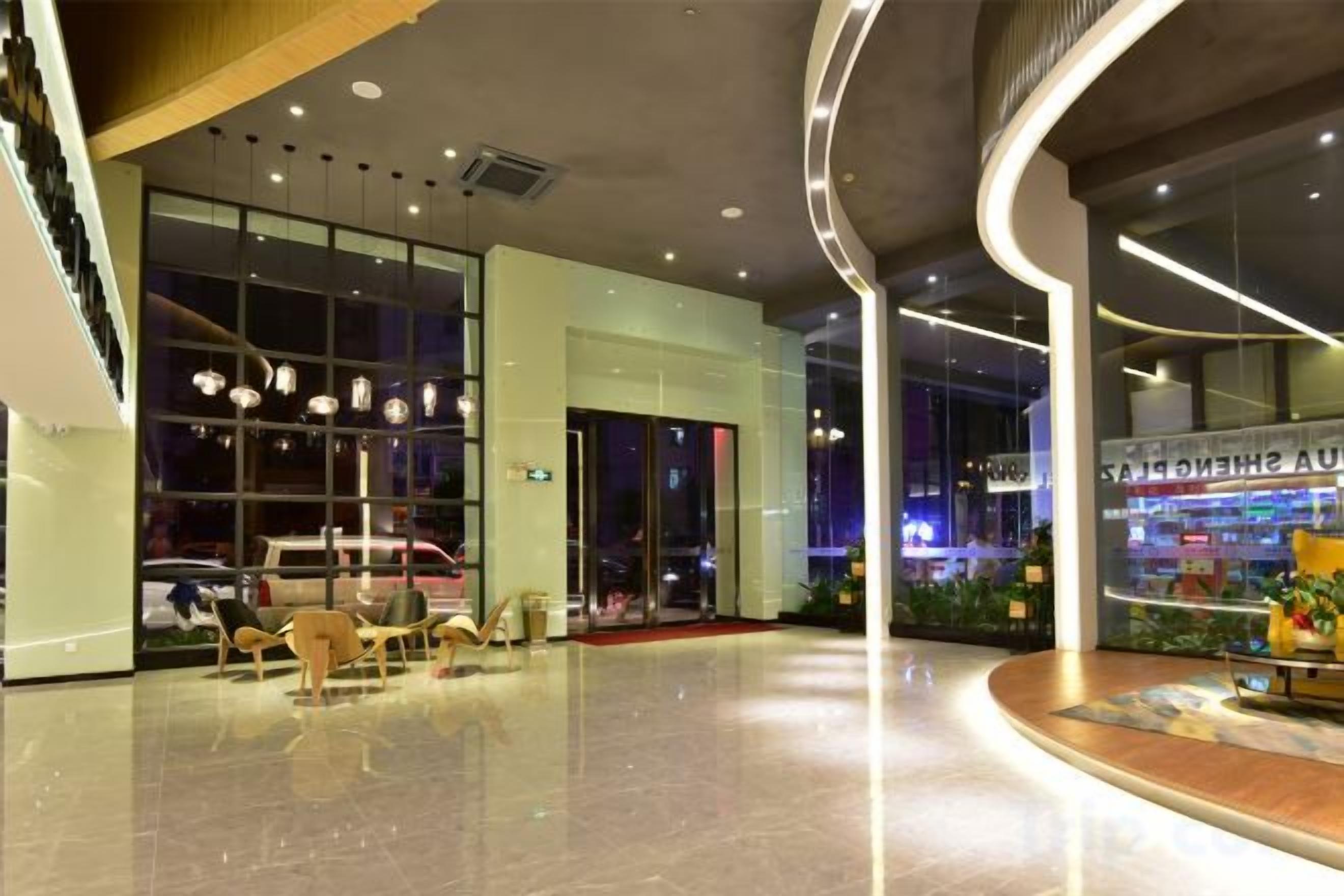 A modern hotel lobby with a curved ceiling, seating area, and a glass storefront.