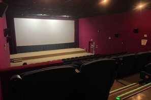 A movie theater with rows of seats, a large screen, and a stage area.