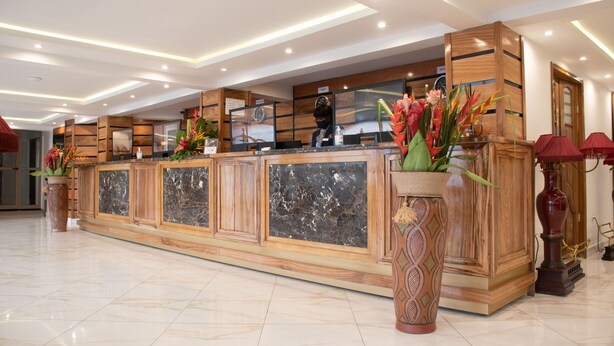 A reception area with a marble counter, wooden paneling, and decorative plants.