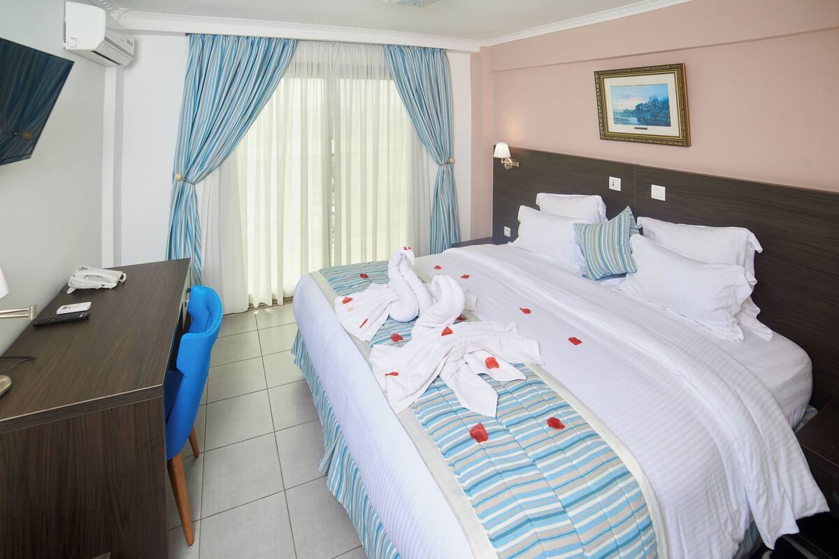 A hotel room with a bed, a desk, a chair, and a window with curtains.