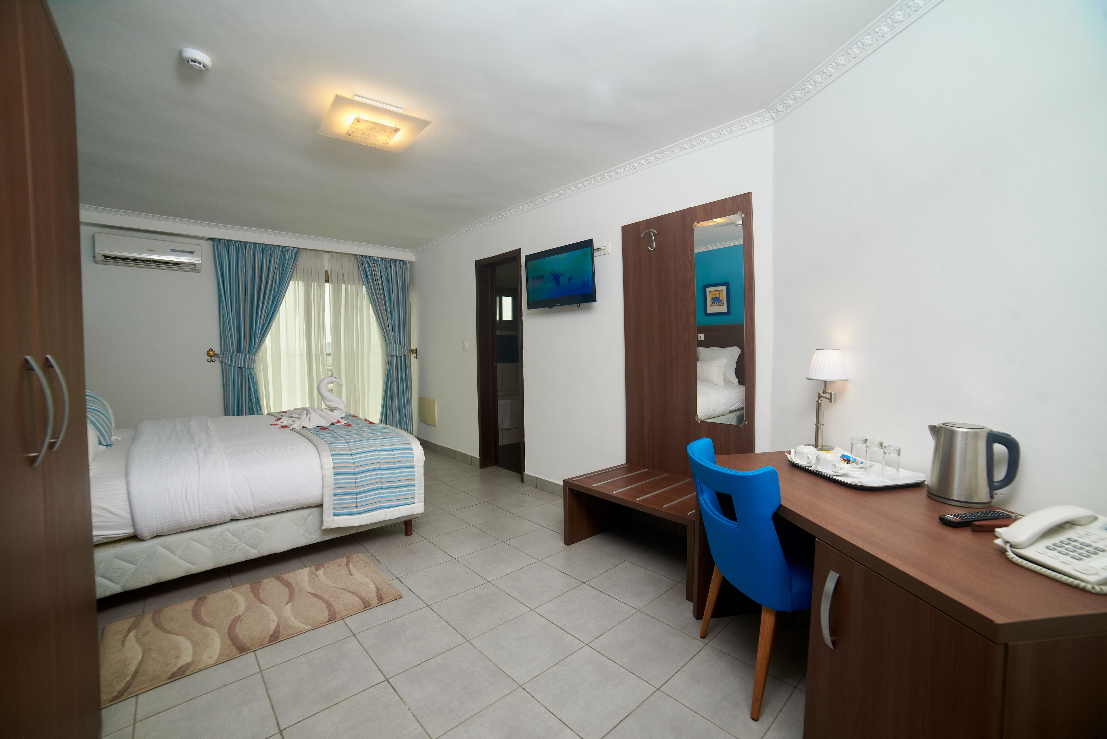 A hotel room with a bed, a desk with a chair, a television, and a coffee maker.