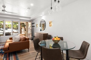 Un salon moderne avec une table à manger en verre, des canapés en cuir et une grande fenêtre donnant sur l’extérieur.