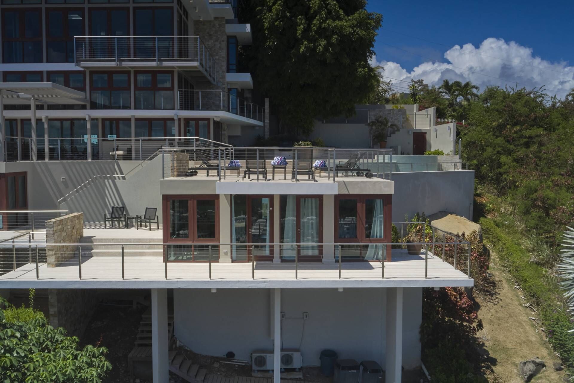 Ein modernes, mehrstöckiges Gebäude mit Dachterrasse, großen Fenstern und einer Treppe, die zu den oberen Stockwerken führt.