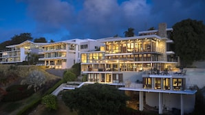 Et moderne hotel med flere etager, fladt tag, store vinduer og udendørs siddepladser.