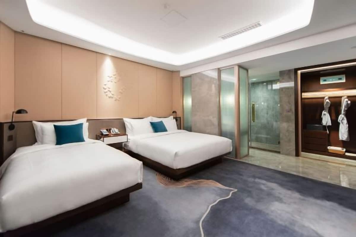 Habitació d'hotel moderna amb dos llits, un mirall gran i vista a una botiga de roba.