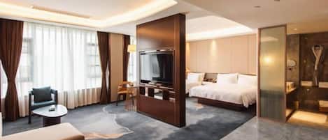 A modern hotel room with a bed, a TV, a seating area with a sofa and a small table, and a large window with curtains.