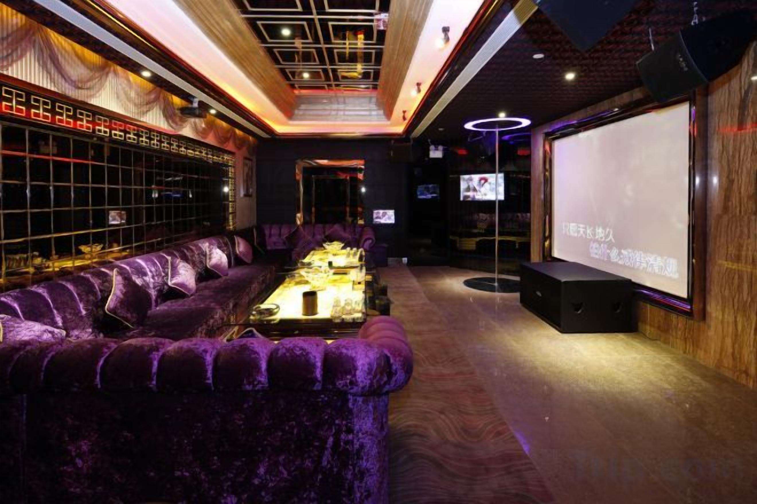 A room with a purple sofa, a projector screen, and a bar area with shelves.
