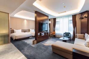 Una habitación de hotel moderna con cama, televisor, sofá y una pequeña mesa.