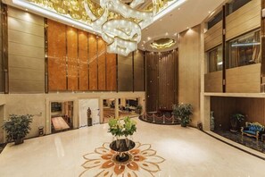 Eine großzügige Lobby mit einem zentralen Blumendekor, einer Kandelaber und einem Empfangstresen.