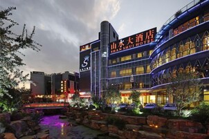 A hotel with a prominent sign, a water feature in the foreground, and a modern architectural design.