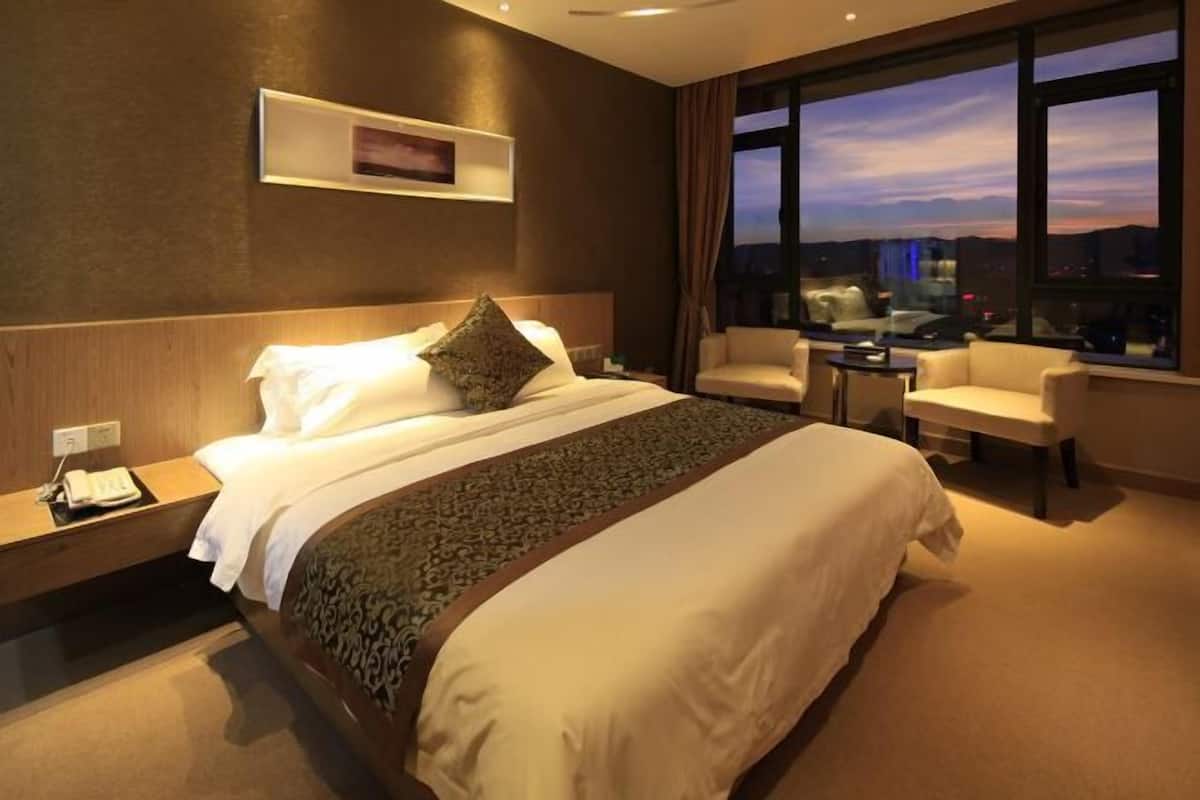 Habitació d'hotel amb un llit gran, una taula de treball, una cadira i vista a la ciutat.