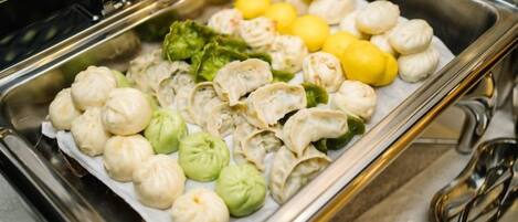 A buffet with various food items including dumplings, broccoli, and lemons.