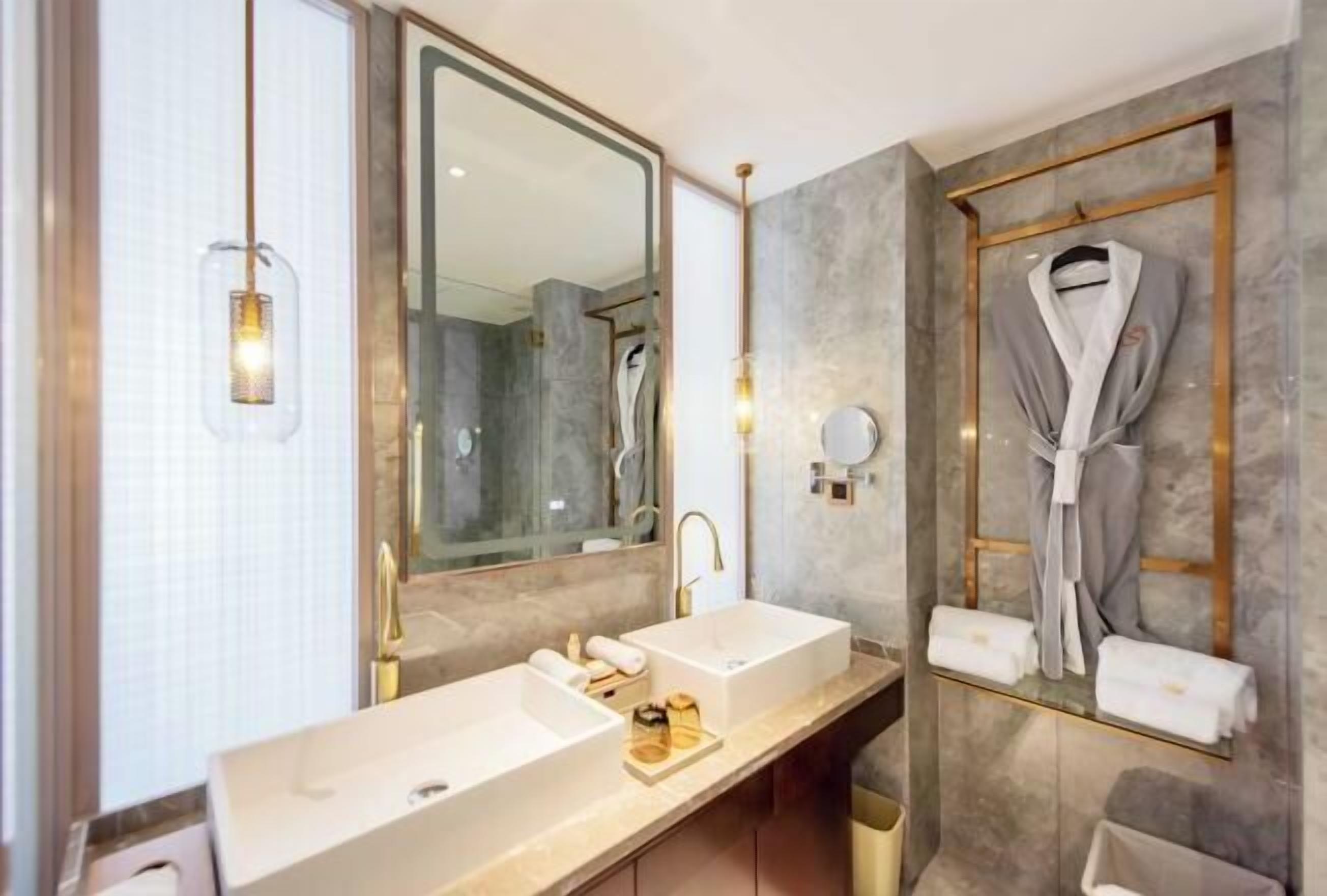 A modern bathroom with two sinks, a large mirror, and a robe rack.