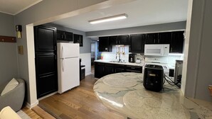 A modern kitchen with black cabinets, a white refrigerator, a microwave, and a coffee maker. - Cozy, Modern Escape; PlayStation 5 and King Suite (Cincinnati)