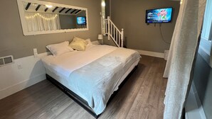 A bedroom with a bed, a ceiling fan, a TV, and a staircase. - Cozy, Modern Escape; PlayStation 5 and King Suite (Cincinnati)