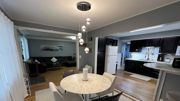 A modern kitchen with a marble island, black cabinets, and a dining area with a round table and chairs. - Cozy, Modern Escape; PlayStation 5 and King Suite (Cincinnati)