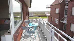 A balcony with a table and chairs, a sofa, and a view of the countryside. - 107-3 Holiday apartment Klabautermann - 107-3 Klabautermann (Juist)