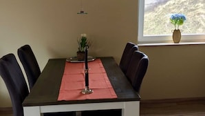 A dining table with a red placemat, black chairs, and a vase with flowers on a windowsill. - 107-3 Holiday apartment Klabautermann - 107-3 Klabautermann (Juist)