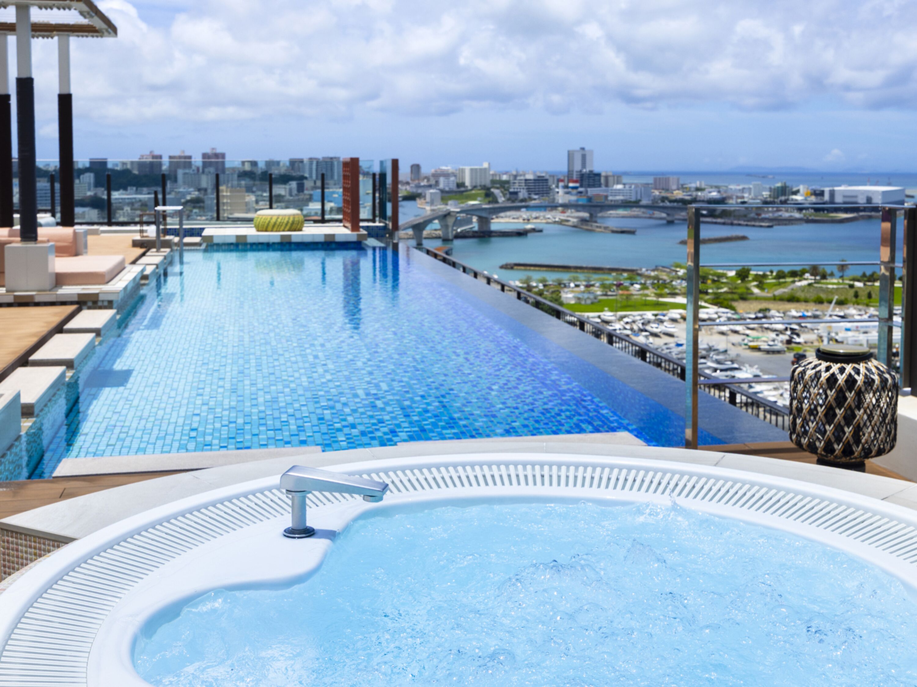 A rooftop infinity pool with a city view, a hot tub, and a lounge area.
