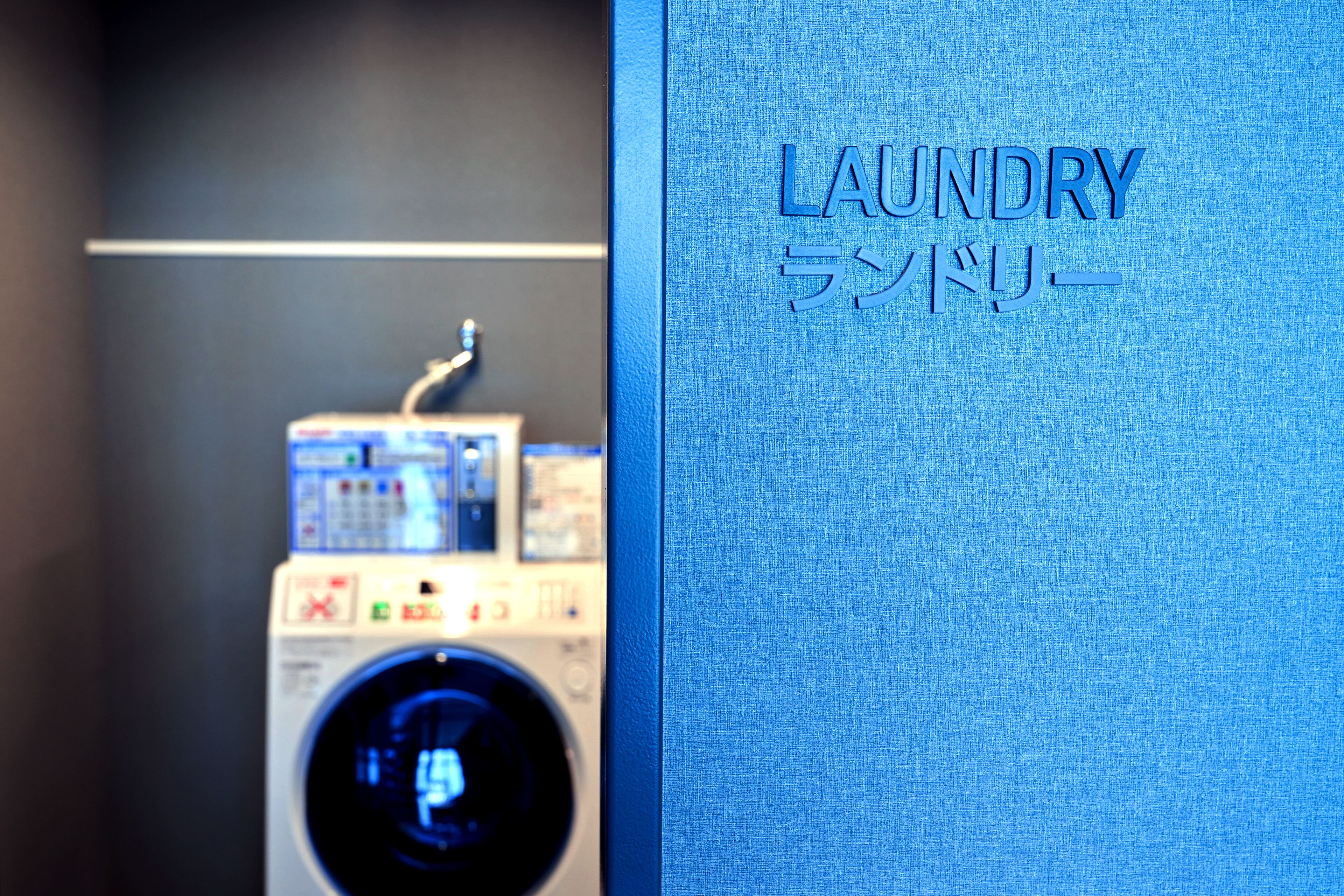A blue wall with the word "LAUNDRY" and its Japanese translation.