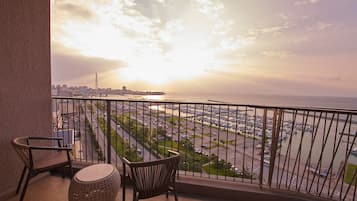 A balcony with a view of a marina and cityscape during sunset.