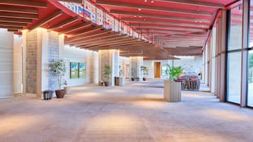 A spacious lobby with a high ceiling, large windows, and potted plants.