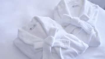 Two white bathrobes tied with a bow on a white pillow.