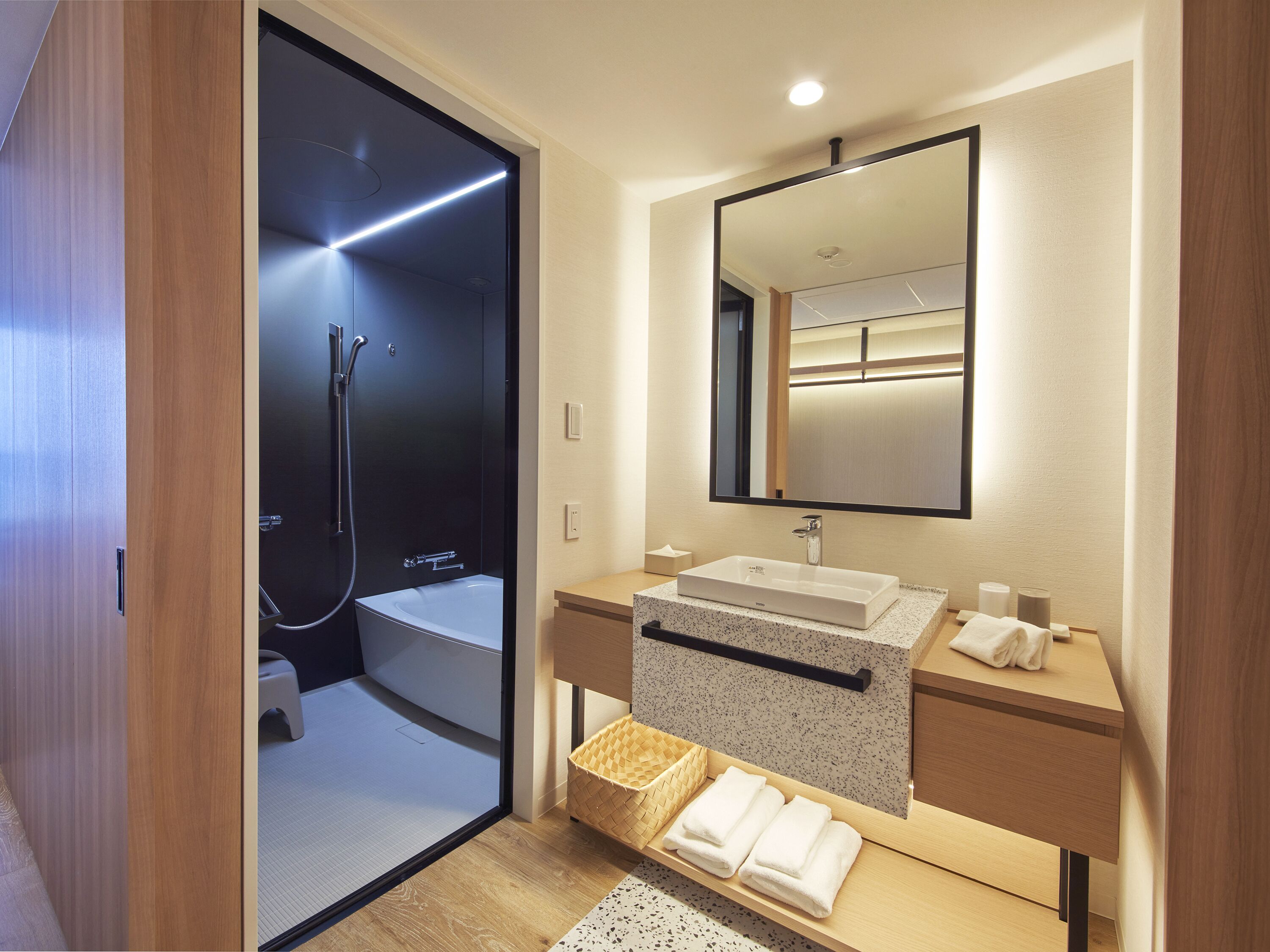A modern bathroom with a walk-in shower, a large mirror, and a wooden vanity.