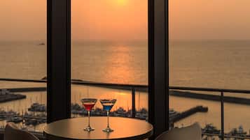 A sunset view from a balcony with two martini glasses on a table.