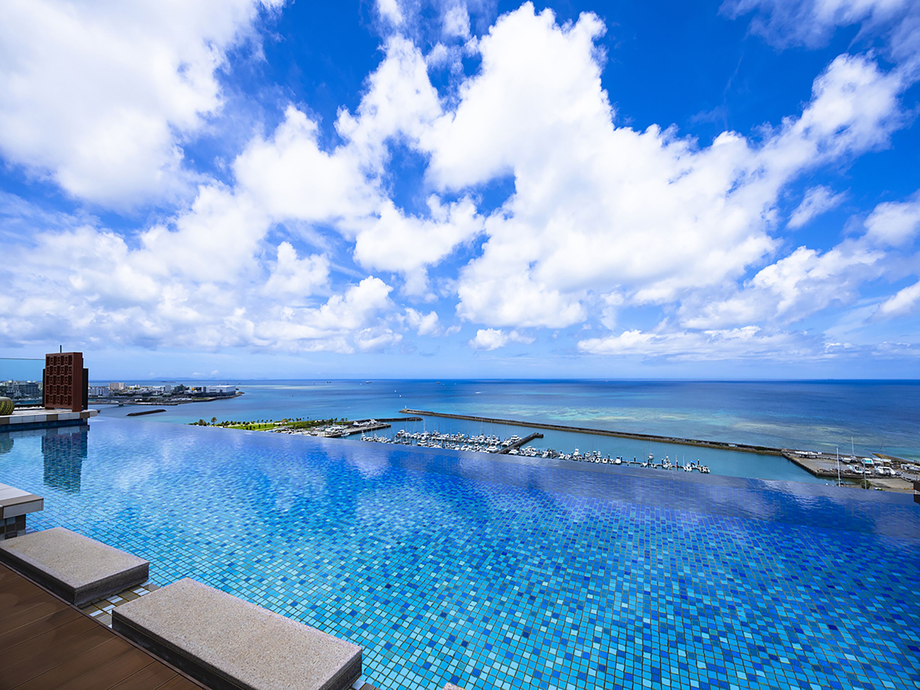 An infinity pool with a clear view of the ocean and marina.