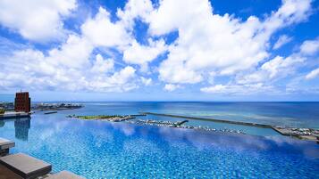 An infinity pool with a clear view of the ocean and marina.