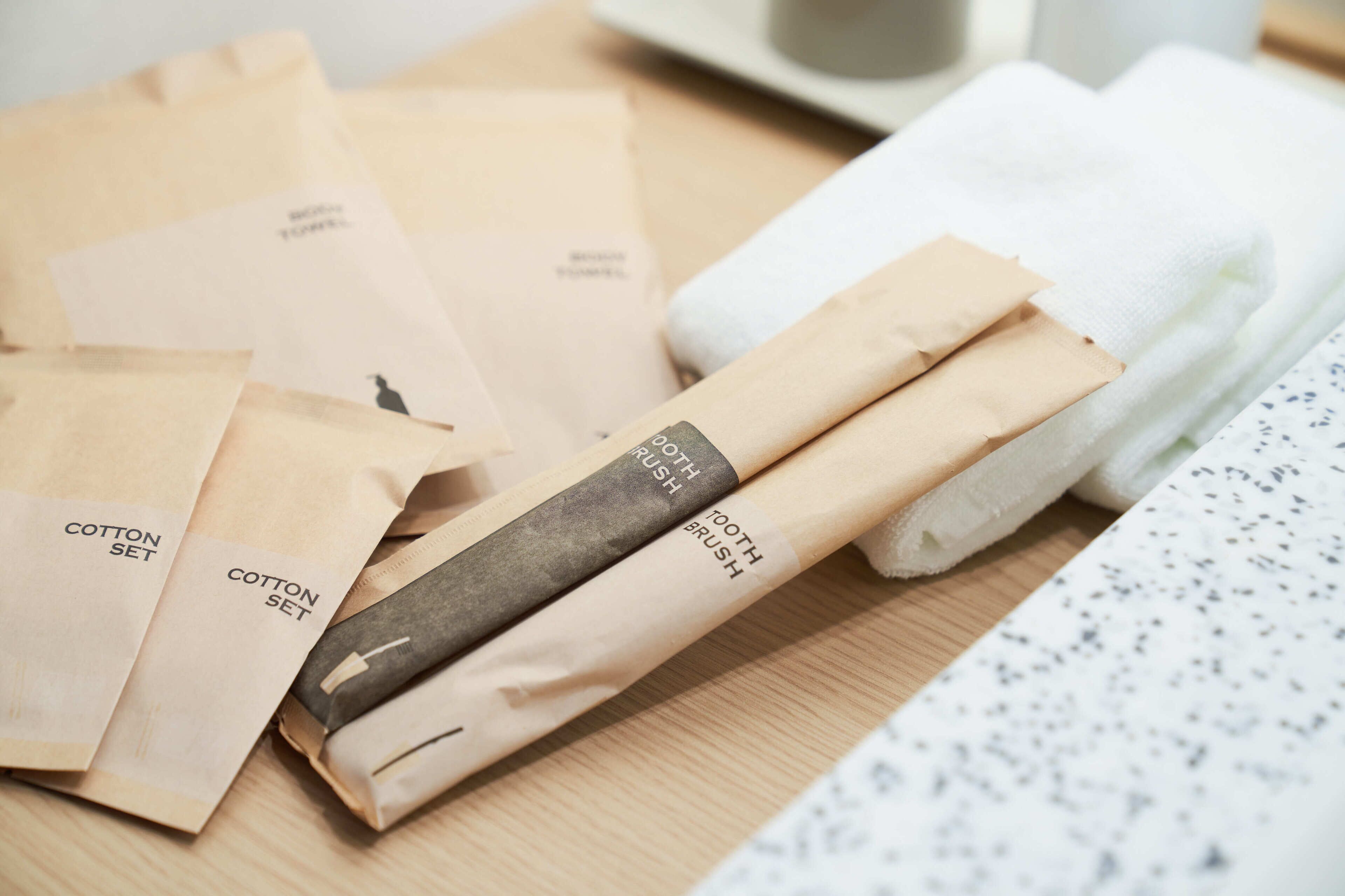 A wooden table with several brown paper bags labeled "Cotton Set" and "Tooth Brush."