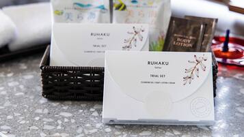 A basket containing a white box labeled 'RUHAKU' with 'TRIAL SET' and 'CLEANSING OIL / SOAP / LOTION / CREAM' text, and a card with similar branding.