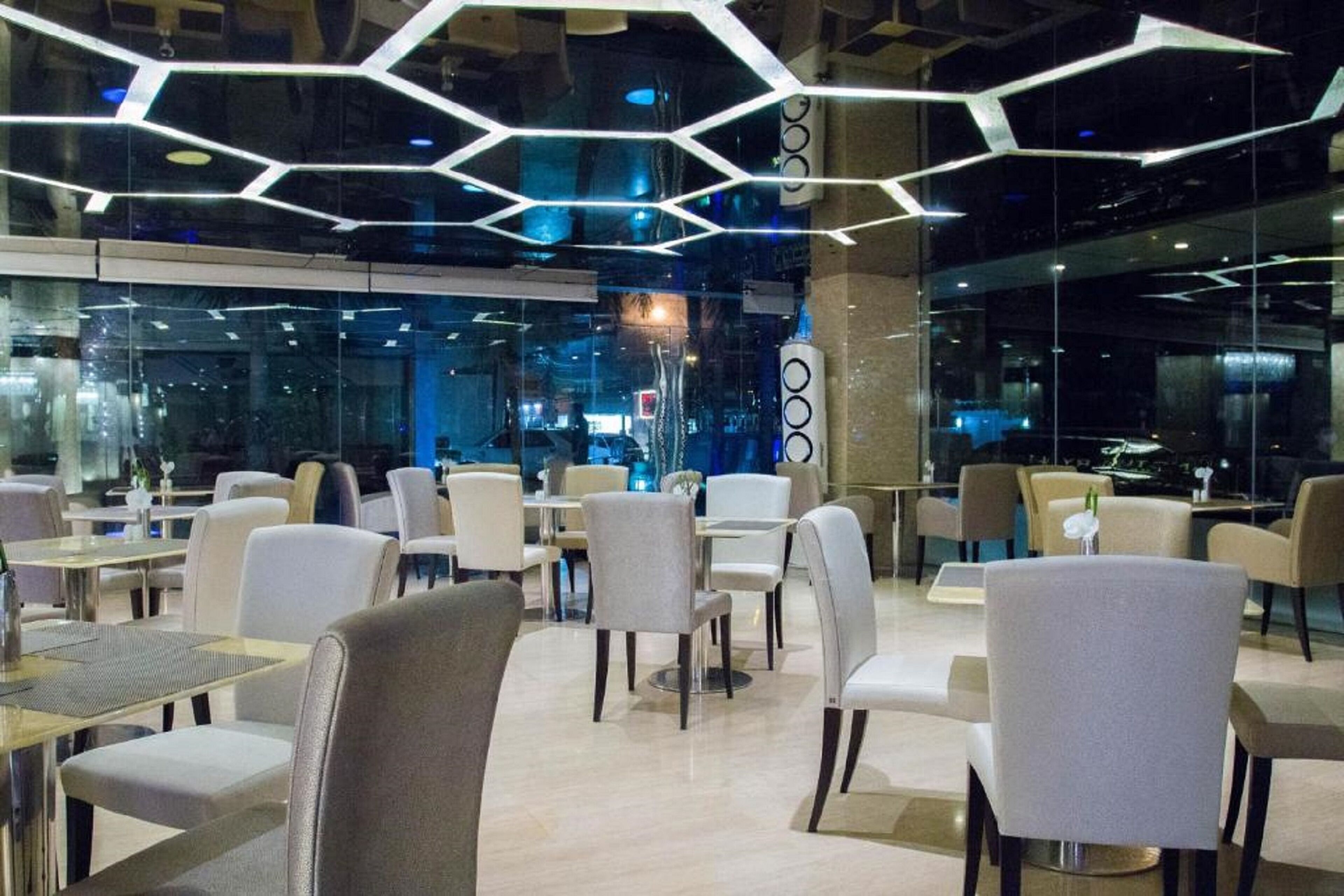 A modern restaurant with hexagonal ceiling lights, glass walls, and a clean, contemporary interior.