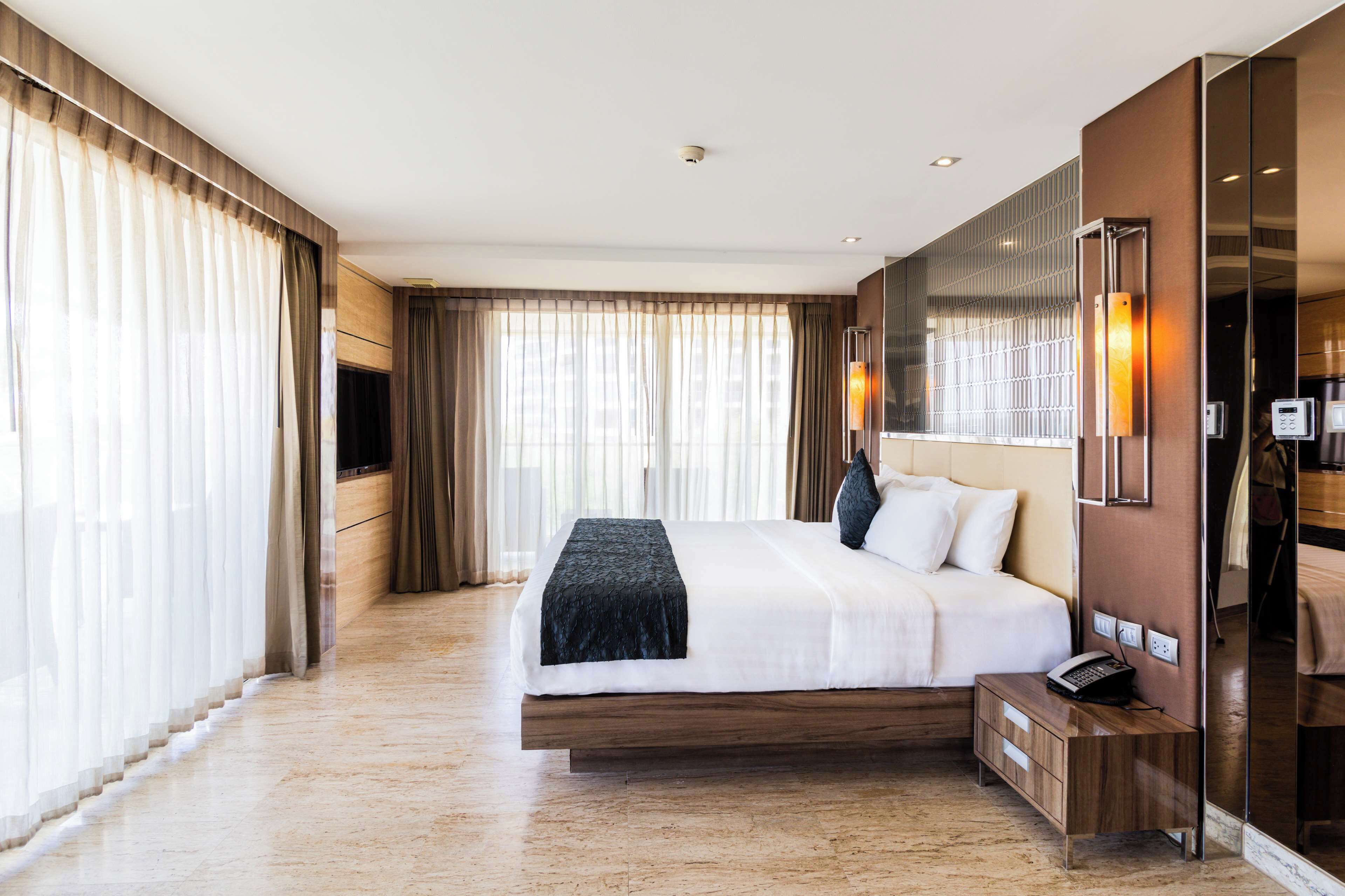 Ein modernes Hotelzimmer mit einem großen Bett, einem Nachttisch mit Telefon und einem Spiegel.