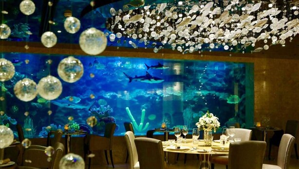 An indoor dining area with an aquarium backdrop, tables set for dining, and decorative bubbles. - The Sanctuary Resort Pattaya, BW Signature Collection (Pattaya)