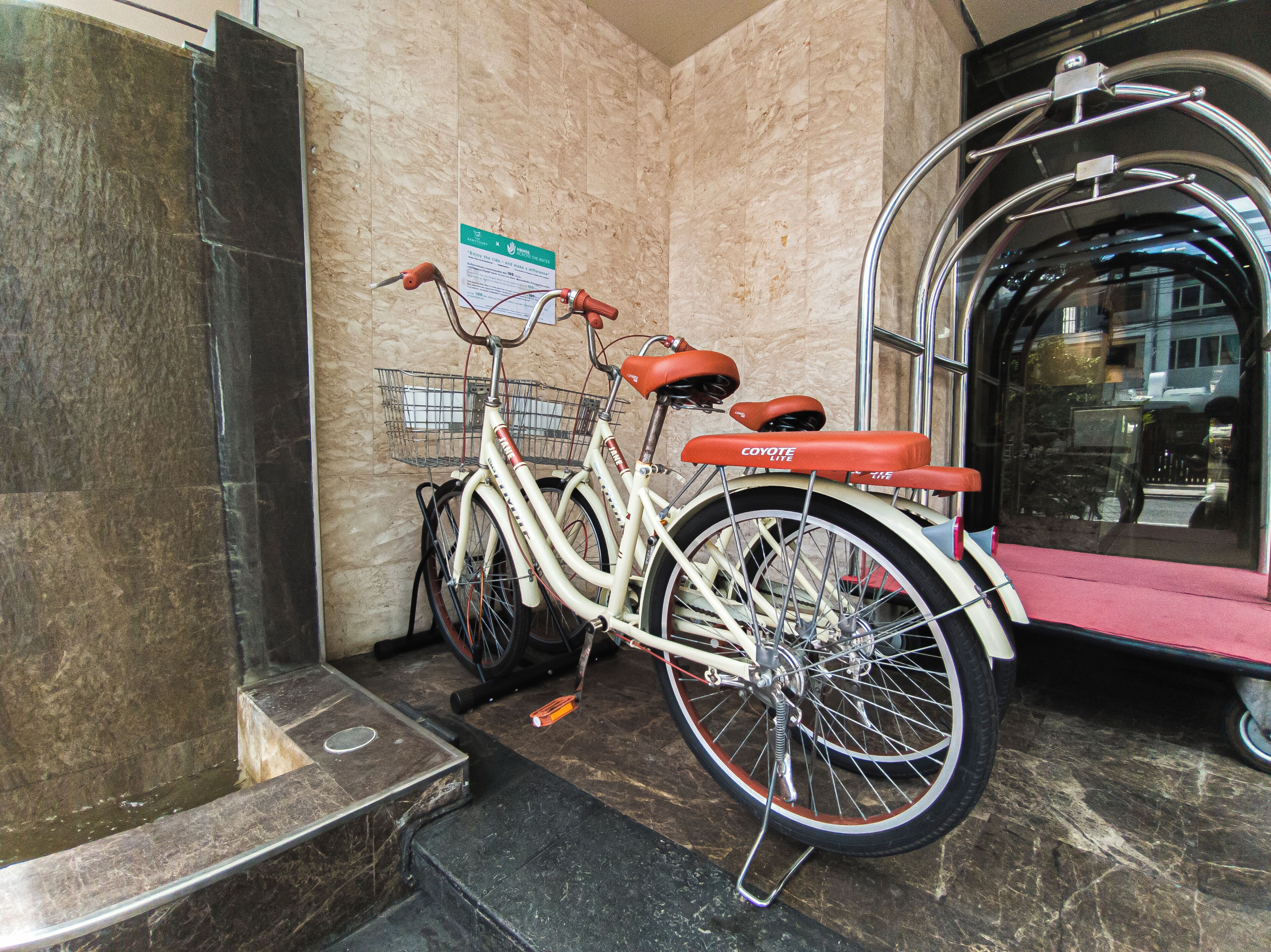 A bicycle parked inside a building with a marble wall and a metal door.