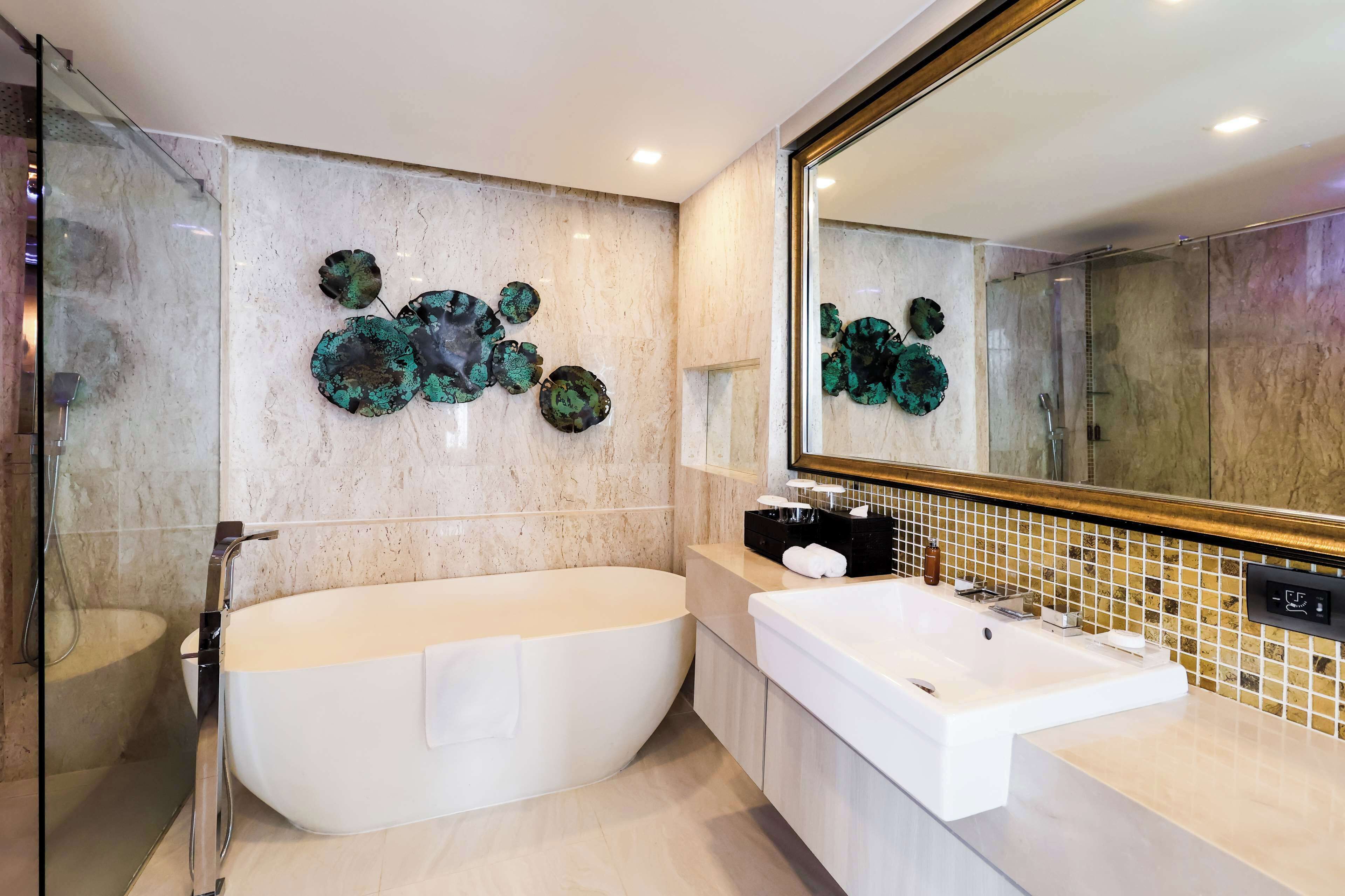Un baño moderno con una bañera independiente, un espejo grande y decoración mural.