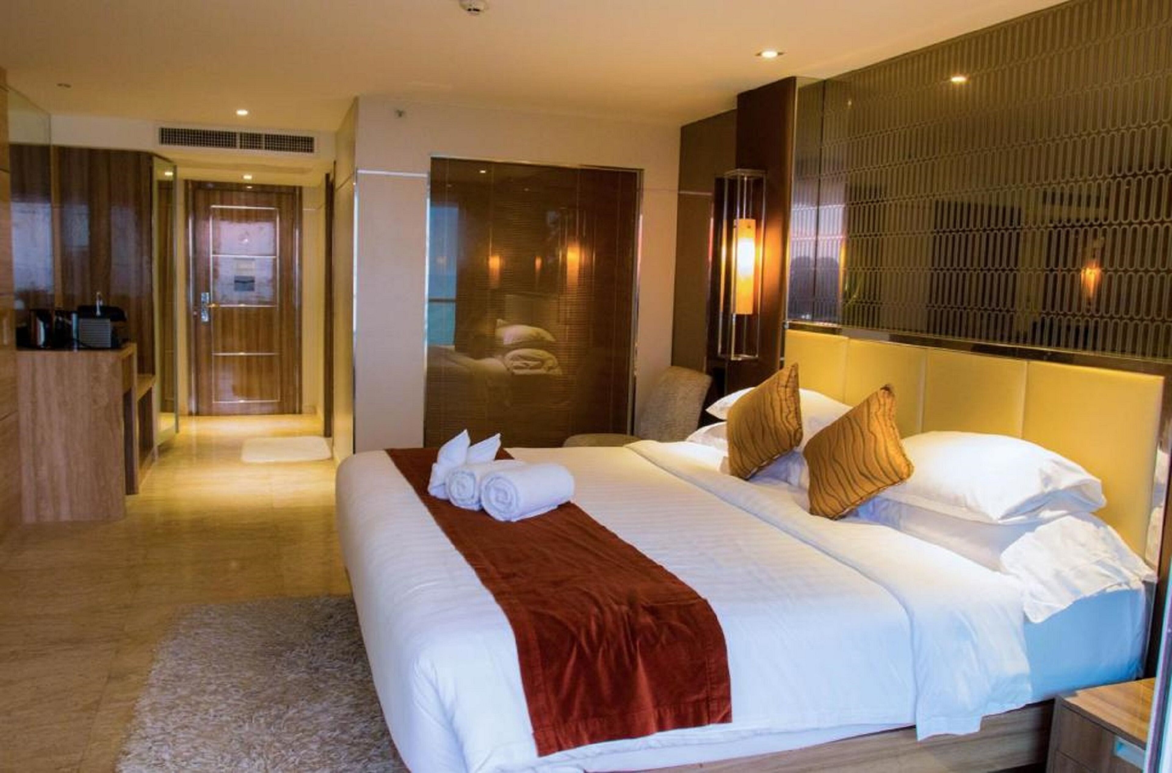 Quarto de hotel com uma cama grande, área de estar e banheiro.