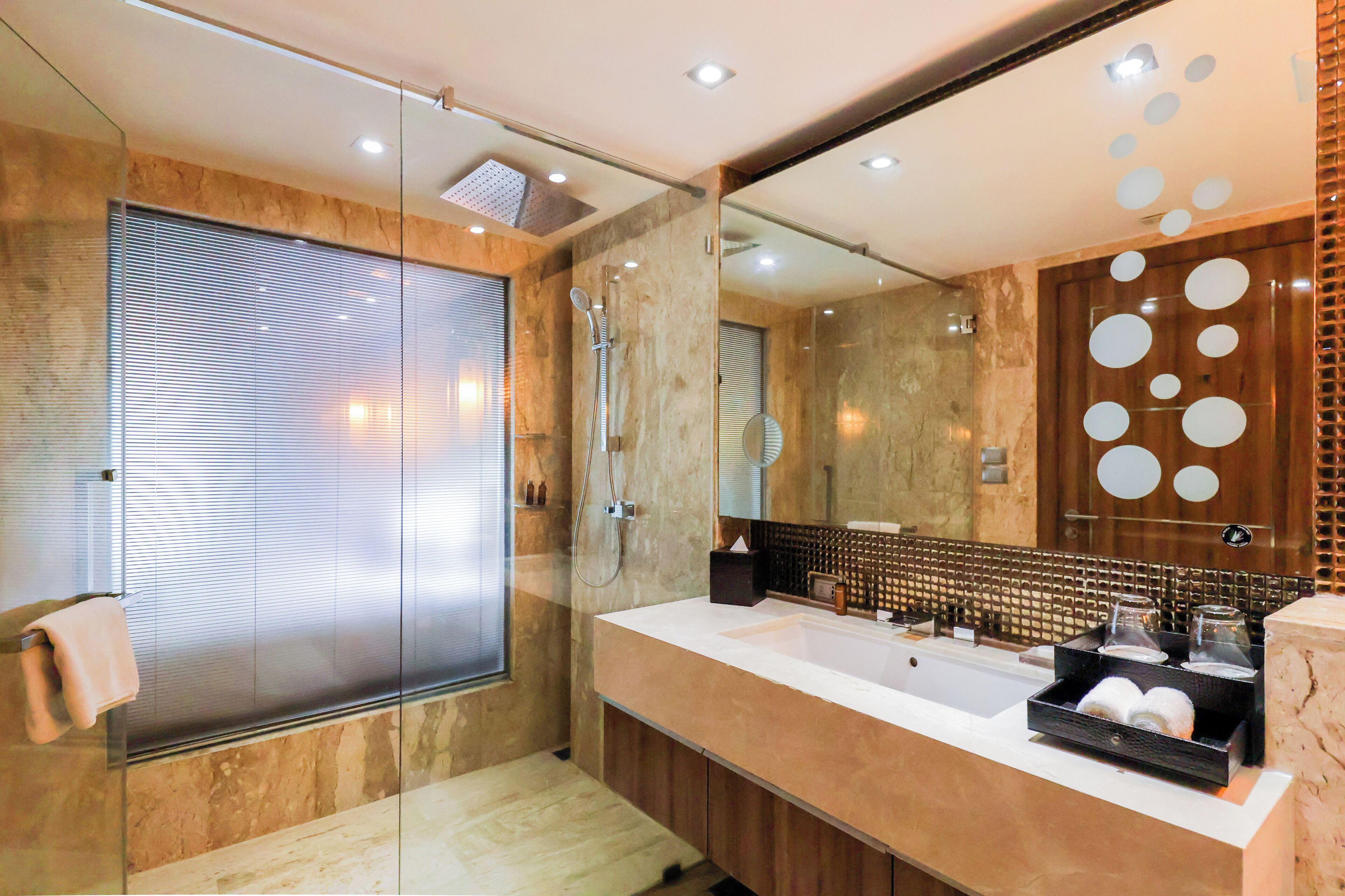 A modern bathroom with a glass shower enclosure, a large mirror, and a vanity with toiletries.