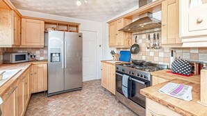 Une cuisine moderne avec des meubles en bois, un réfrigérateur en acier inoxydable, une cuisinière et un four à micro-ondes.