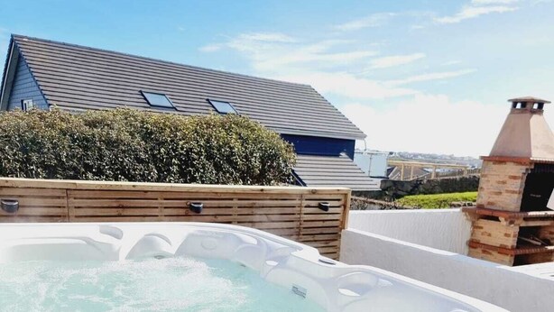 Un bain à remous avec une terrasse en bois et une cheminée en briques en arrière-plan.