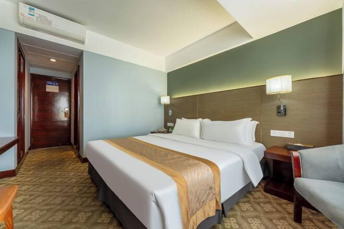 A hotel room with a large bed, bedside tables, a desk, and a chair.