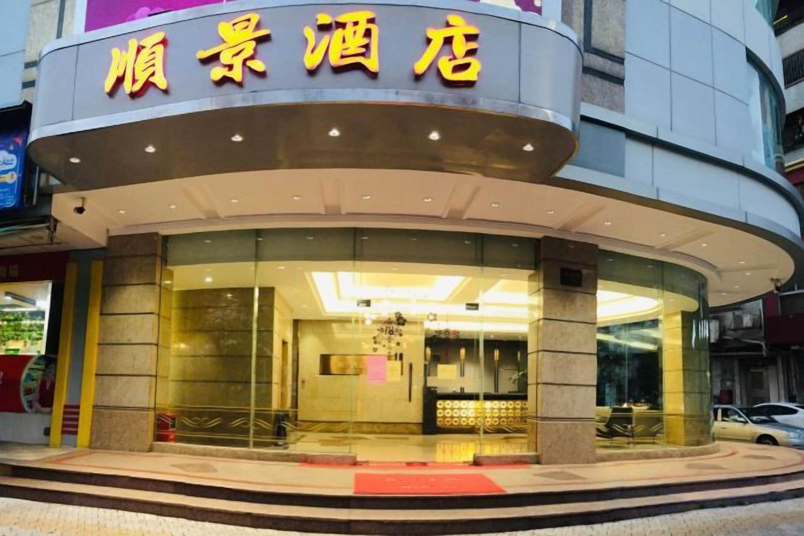 A hotel with a curved facade, large glass windows, and a red carpet entrance.