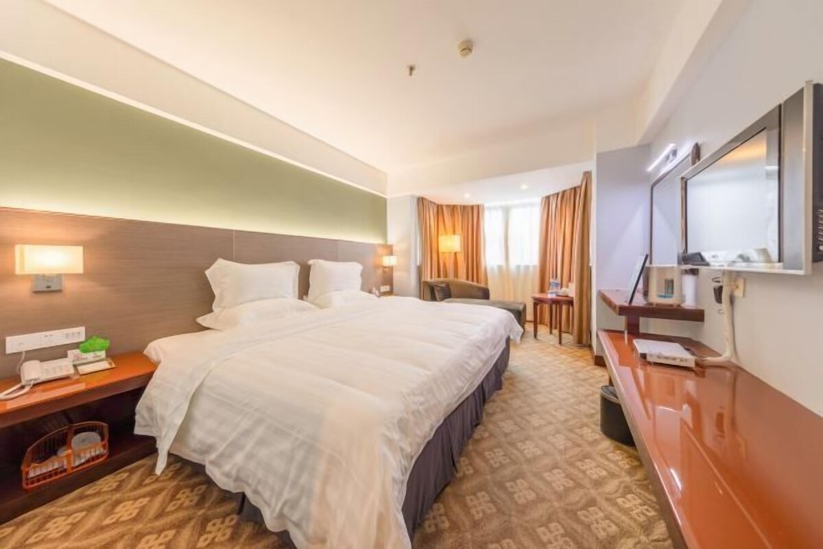 A hotel room with a large bed, bedside tables, a desk, and a mirror.