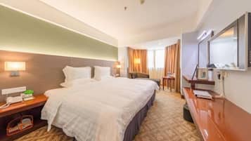 Ein Hotelzimmer mit einem großen Bett, Nachttischen, einem Schreibtisch und einem Spiegel.