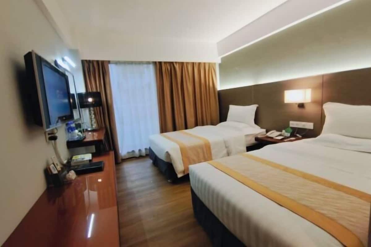 A hotel room with two beds, a TV, a desk, and a nightstand.