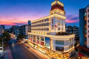 Un hotel de varios pisos con una ubicación destacada en una esquina, amplias ventanas y un balcón en el piso superior.