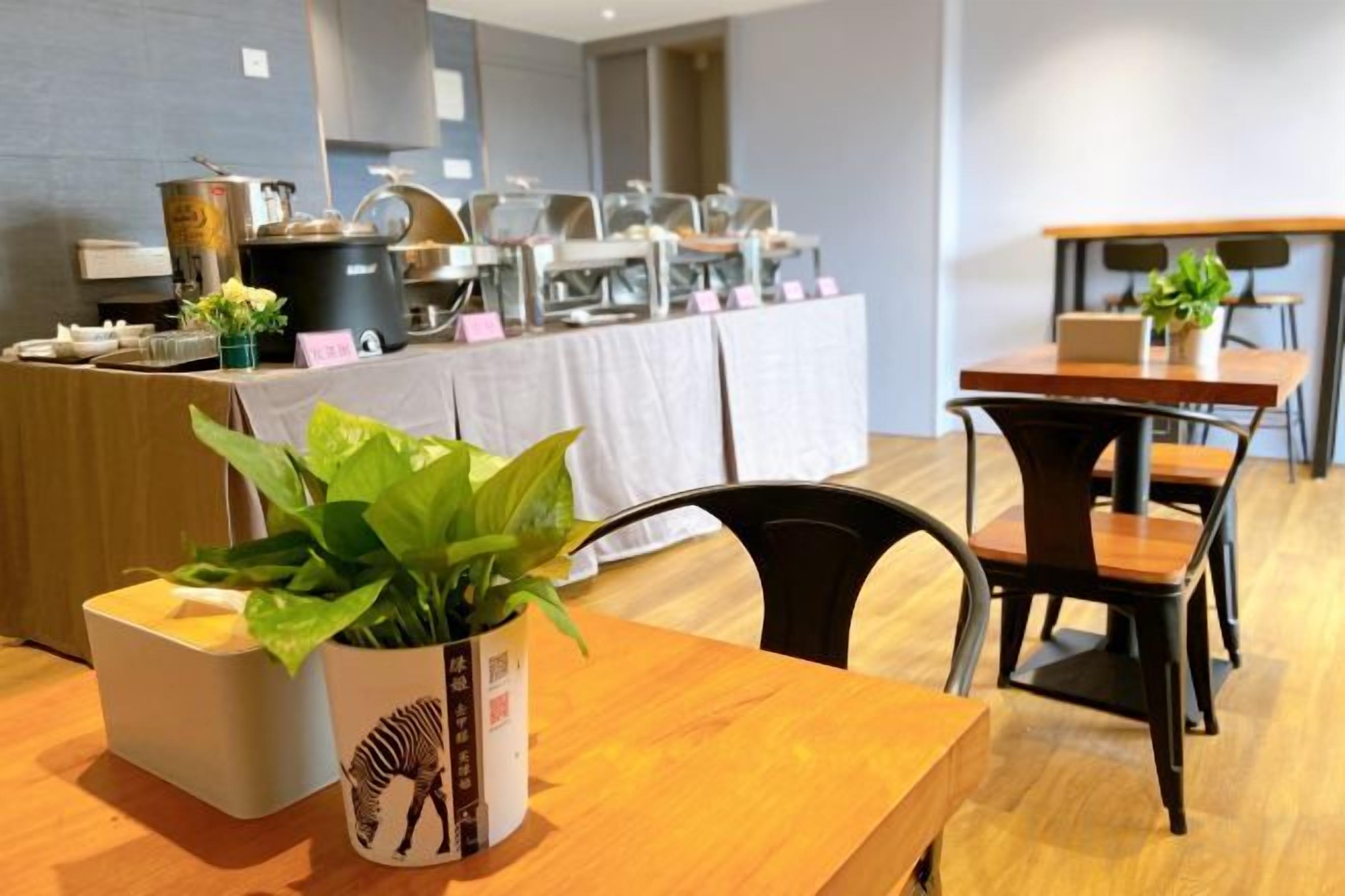 A dining area with a wooden table, chairs, and a buffet line in the background.